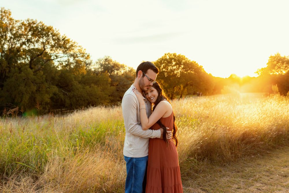 Romantic couple embracing in golden sunset field.