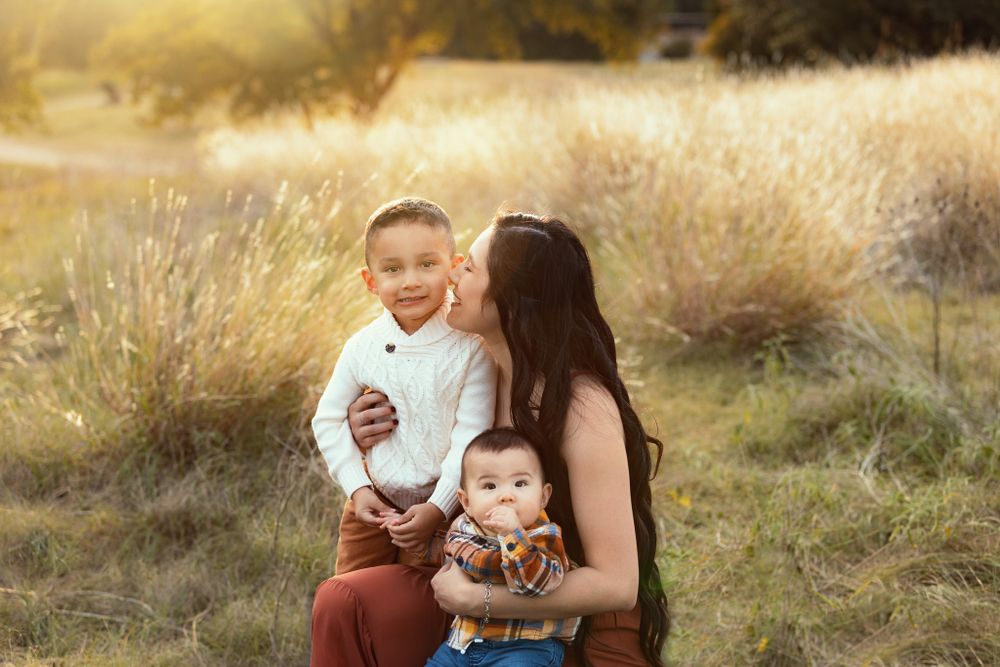 Tender family moment captured outdoors in golden autumn field at sunset.