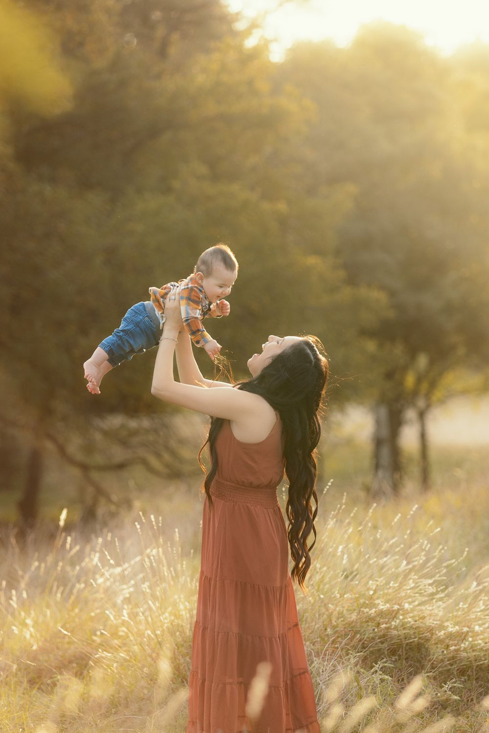 Joyful family moment captured in golden sunlit field with tall grass.