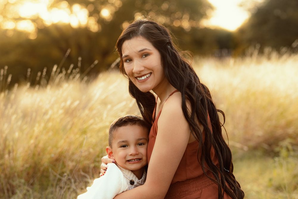 Beautiful family portrait in golden autumn field at sunset.