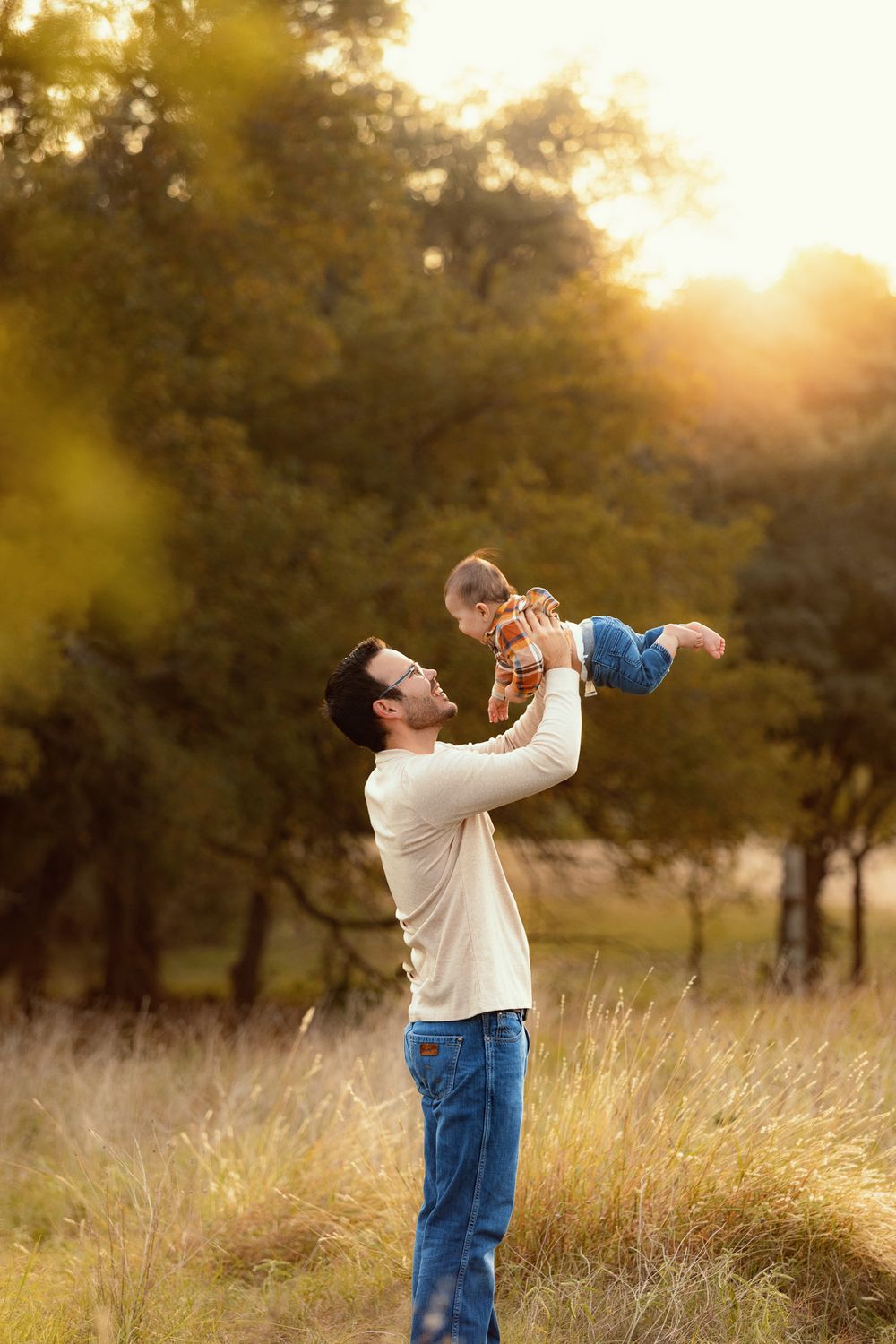 Happy family playtime in sunlit meadow during golden hour.