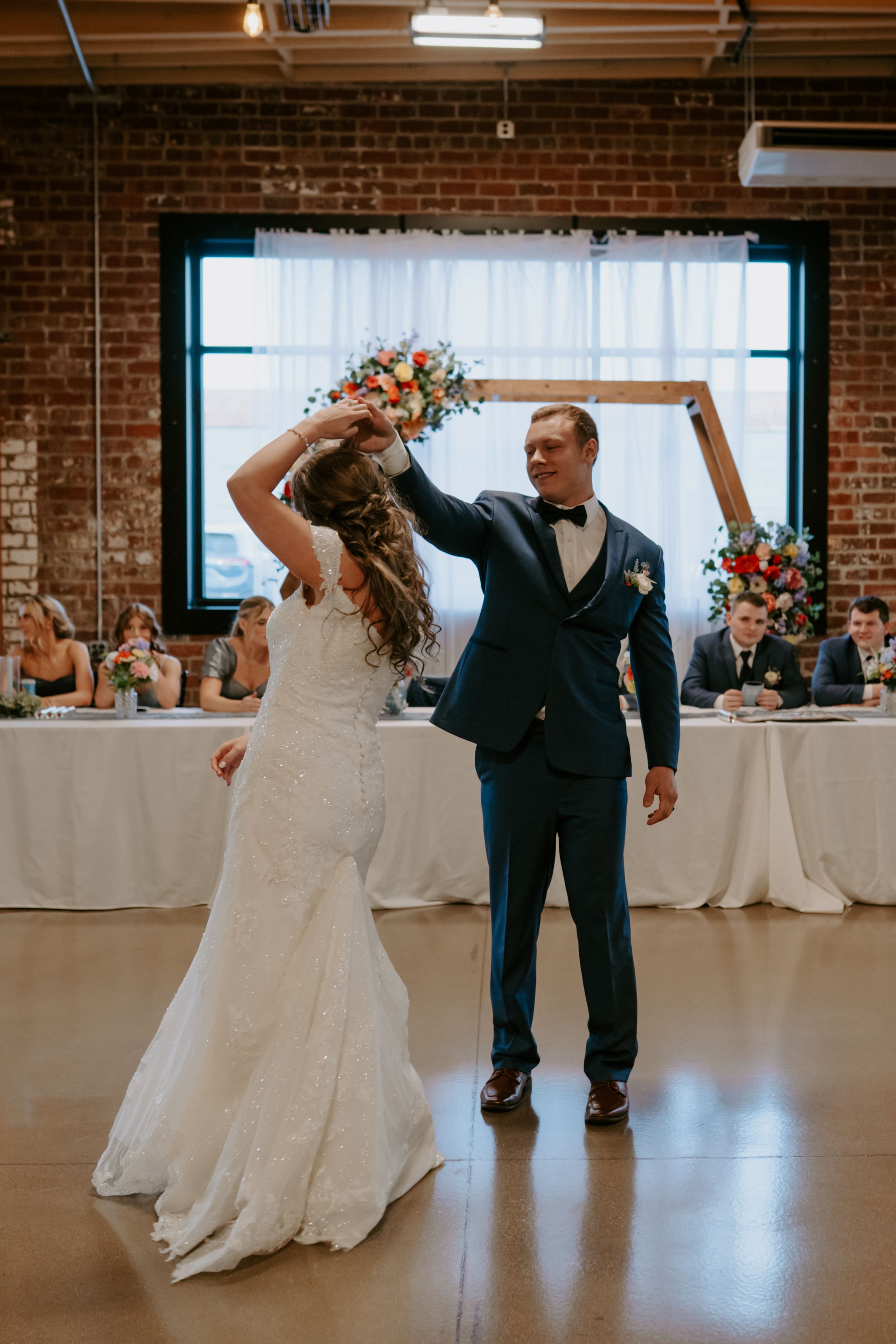 Couple dancing together in spacious brick-walled reception venue.