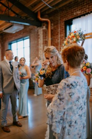 Wedding guests dancing and celebrating in industrial-style reception venue with brick walls.