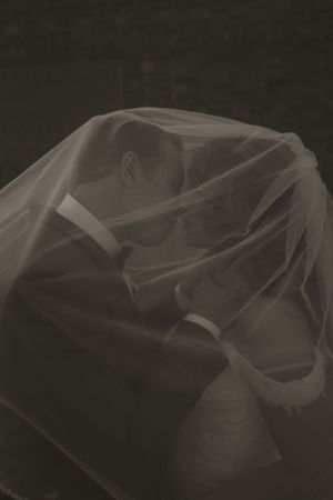 Artistic close-up of flowing white wedding veil fabric in dark lighting.