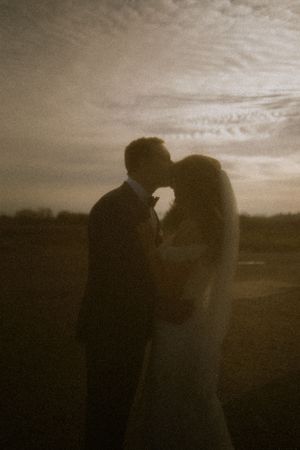 Silhouettes of a couple embracing at sunset against a dramatic sky.