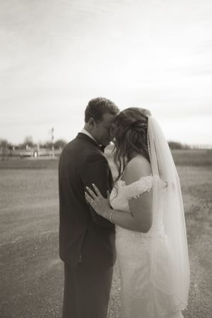 Intimate black and white wedding portrait in an open field setting.