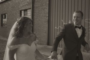 Wedding couple sharing a playful moment against an industrial brick building backdrop.