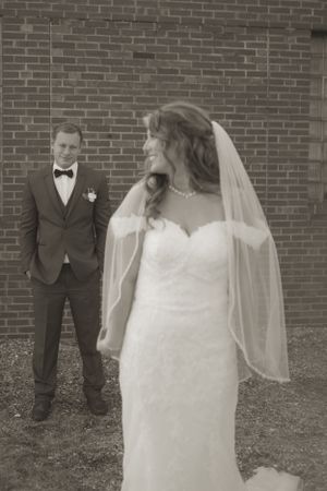 A wedding dress and veil silhouette against a brick wall background.