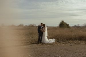 Distant view of a couple in wedding attire standing in a natural field landscape.