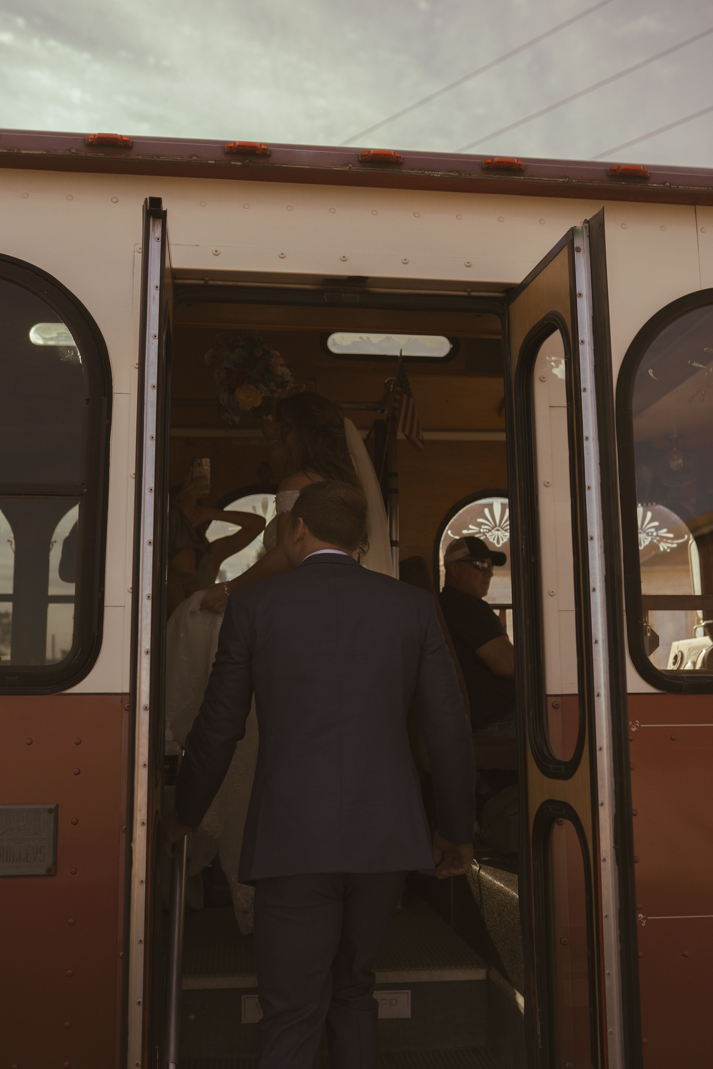 Wedding party members boarding a vintage brown and white passenger van.