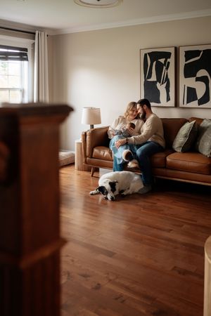 A series of photos showing a person relaxing on a brown leather couch with a dog in a modern living room with hardwood floors.