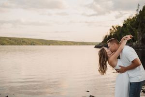 A couple embraces on a dock at sunset, surrounded by scenic waterfront views and natural lighting.