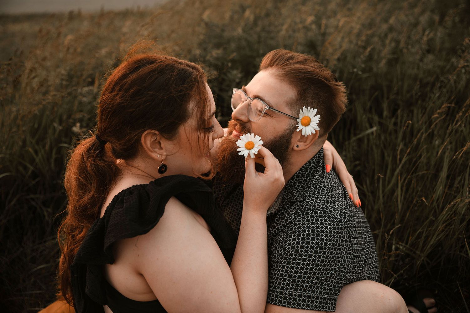 Couple at Outer Harbor Buffalo, NY cuddling in field at golden hour
