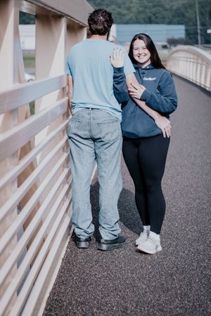 A couple walking together on a bridge wearing jeans and black clothes, shown from waist down.