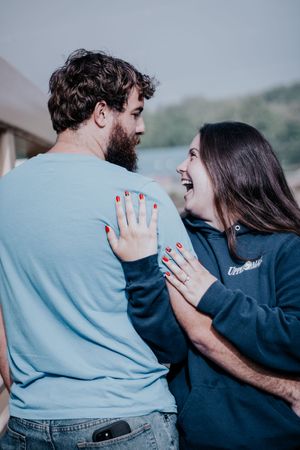 A couple embraces in a romantic photoshoot sequence wearing blue and navy clothing against a blurred outdoor backdrop.