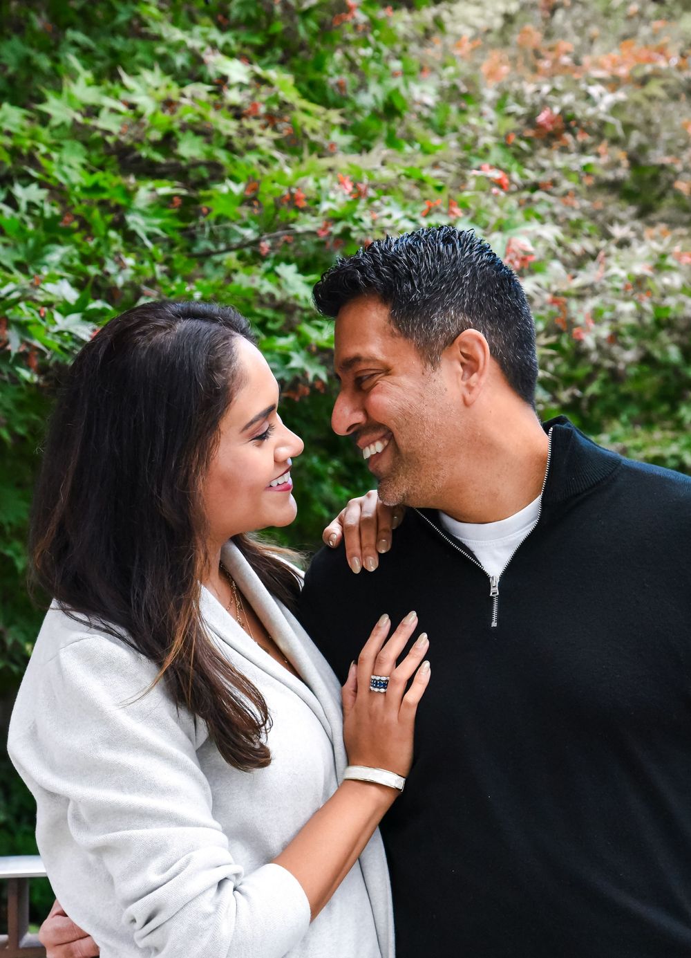 A couple shares intimate moments in a garden setting, dressed in black and white attire during an outdoor photo session.