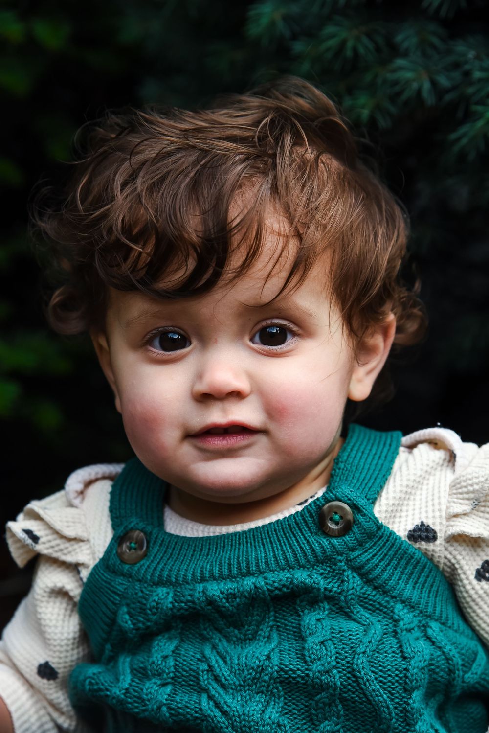 Close-up view of a small child wearing a green knit sweater with cream colored collar detail.