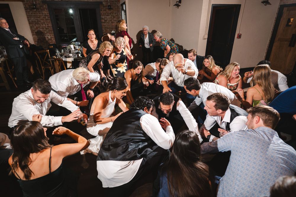 Birdseye photo of bride and groom dancing in crowd of guests in industrial reception space at Drowned Lands Brewery in Warwick, NY.