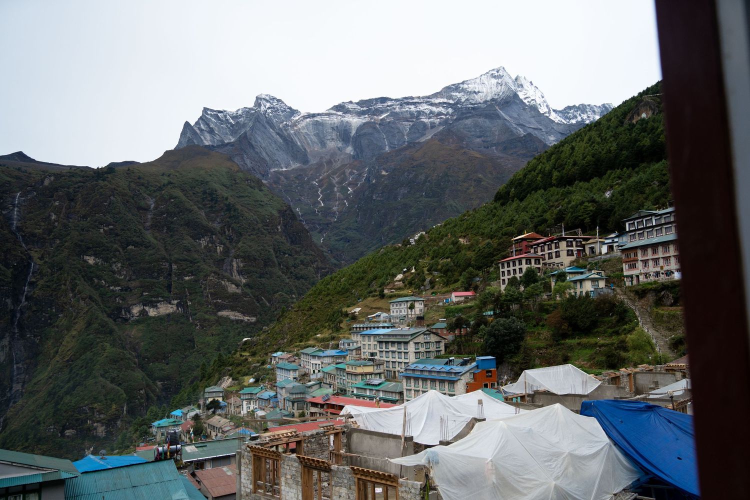 Colorful buildings of a mountain village nestled beneath snow-capped Himalayan peaks.