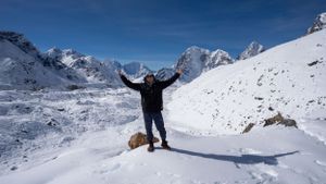 Snow-covered mountain landscape with climbers making their way across vast white terrain.