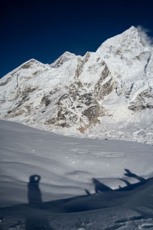 Long shadows cast on pristine snow with towering mountain peaks looming in the background.