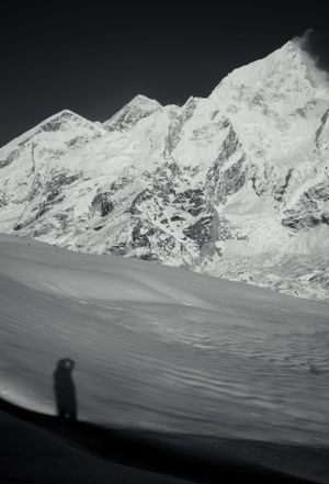Silhouettes cast on snow-covered slopes with majestic mountain ridges in monochrome.