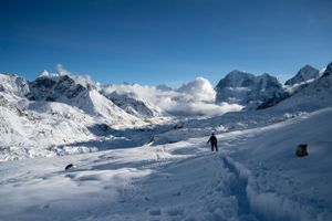 Panoramic winter mountain landscape with skiers traversing vast snowy terrain.