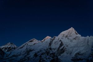 Snow-covered mountain range extending across the horizon under a dark night sky.