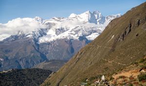 Panoramic view of snow-covered Himalayan peaks rising above brown mountain slopes.