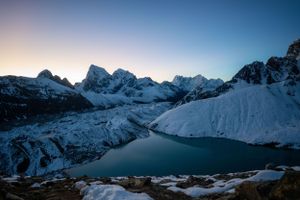 Majestic mountain peaks cast long shadows during sunset in a winter landscape.