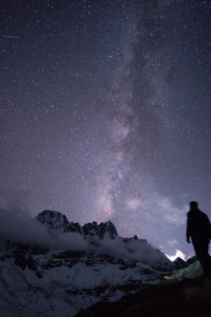 Silhouetted mountain peaks under a starry night sky with visible Milky Way.