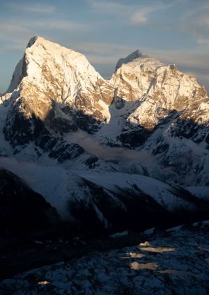 Sunlit snow-capped mountain range glows during golden hour in the Himalayas.