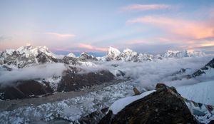 Majestic mountain range with snow-covered peaks reflecting pink sunset light in the Himalayas.