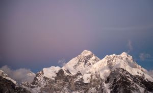 Snow-capped mountain peaks against a dramatic sky during golden hour in a panoramic landscape view.