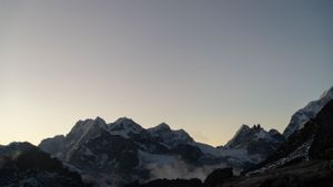 Mountain peaks silhouetted against a clear sky at dusk in a serene mountain range.