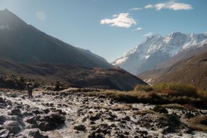 Rugged mountain valley with snow patches and rocky terrain under bright blue skies.