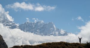 Panoramic view of snow-capped mountain peaks against a bright blue sky with scattered white clouds.