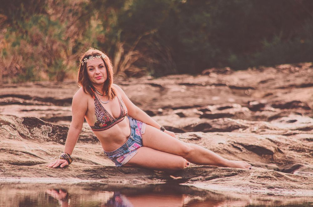 A swimsuit photoshoot on desert rocks with water reflection creating a mirror effect.