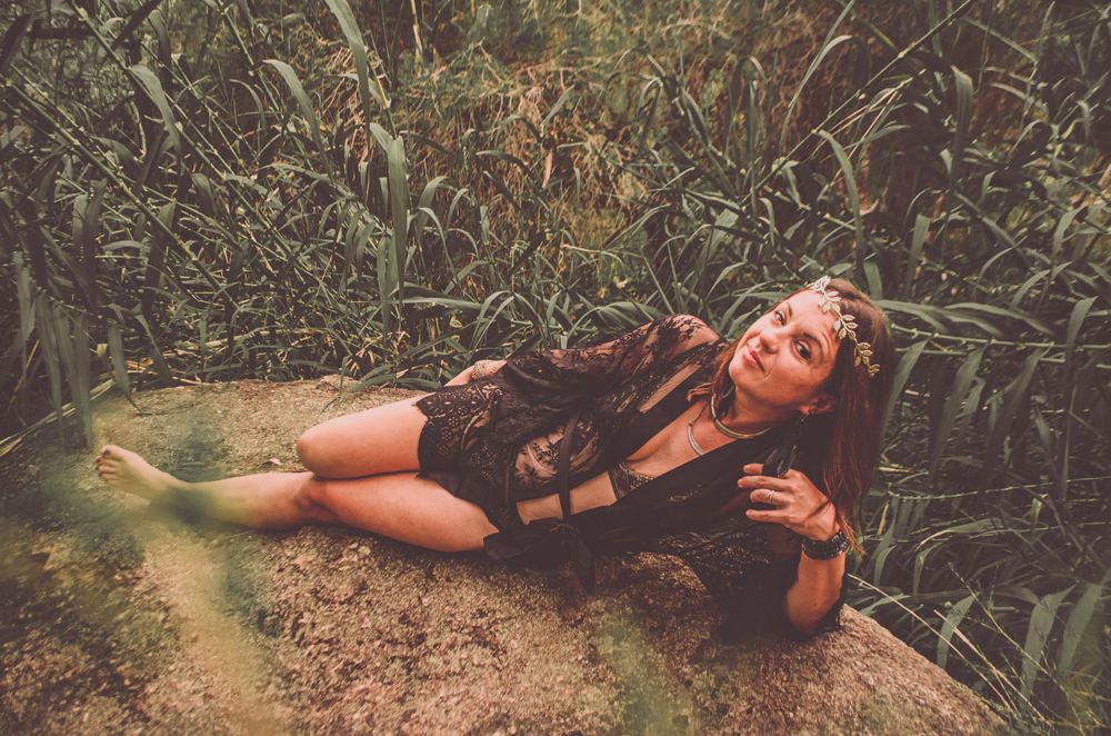 An artistic nature photo with black lace attire against tall reeds and water.