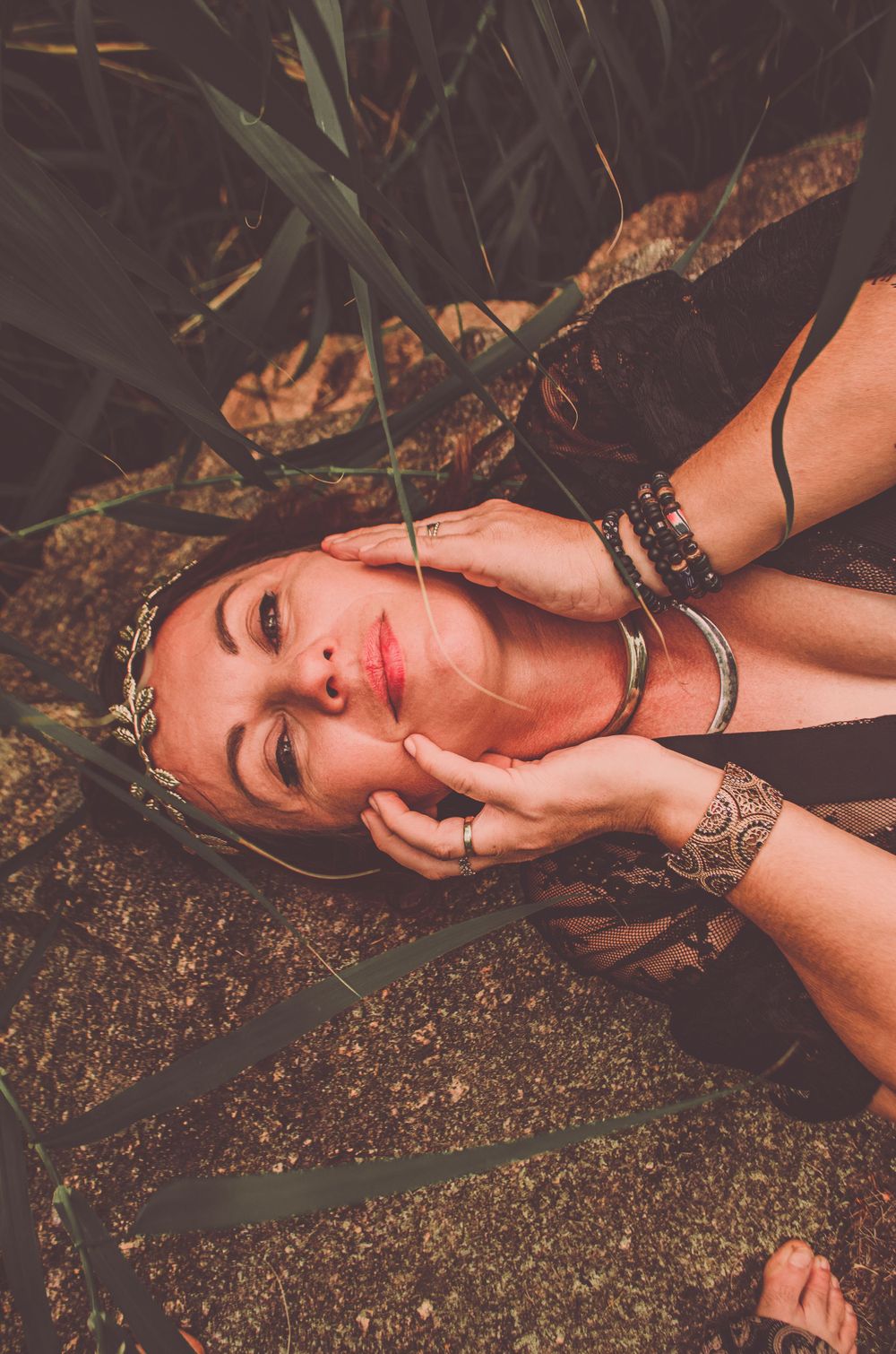 A dramatic portrait showing jewelry and natural styling against an earthy background.