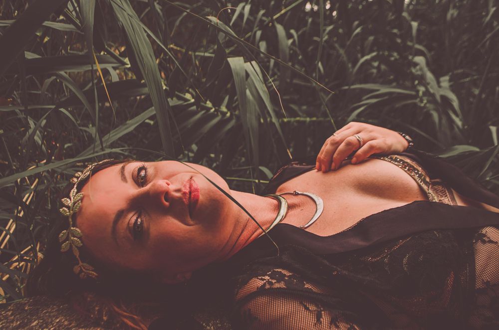 An intimate portrait in black attire set against dark foliage and natural elements.