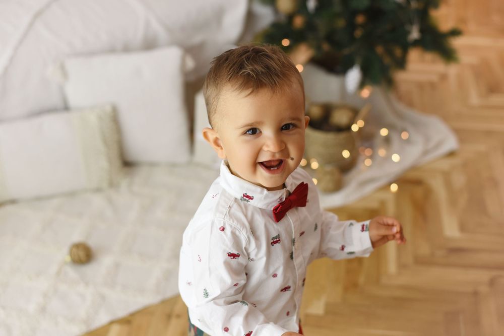 A collage of holiday photos showing a small child in white and red clothing playing near Christmas decorations and lights.