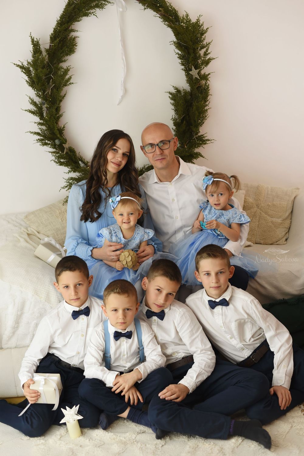 A family portrait series with evergreen garland decor showing different poses on a light colored couch.