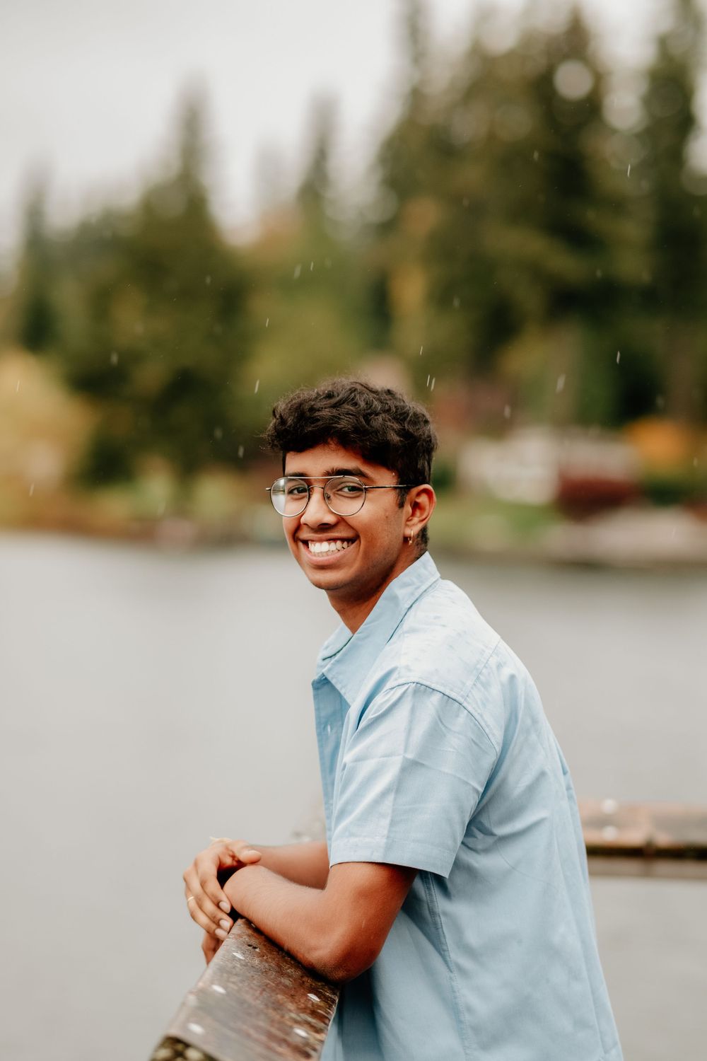 Sequence of a person in light blue shirt sitting by a lake smiling at different angles.