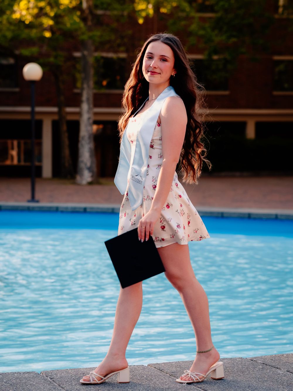 Stylish summer outfit worn near a pool with a black clutch.