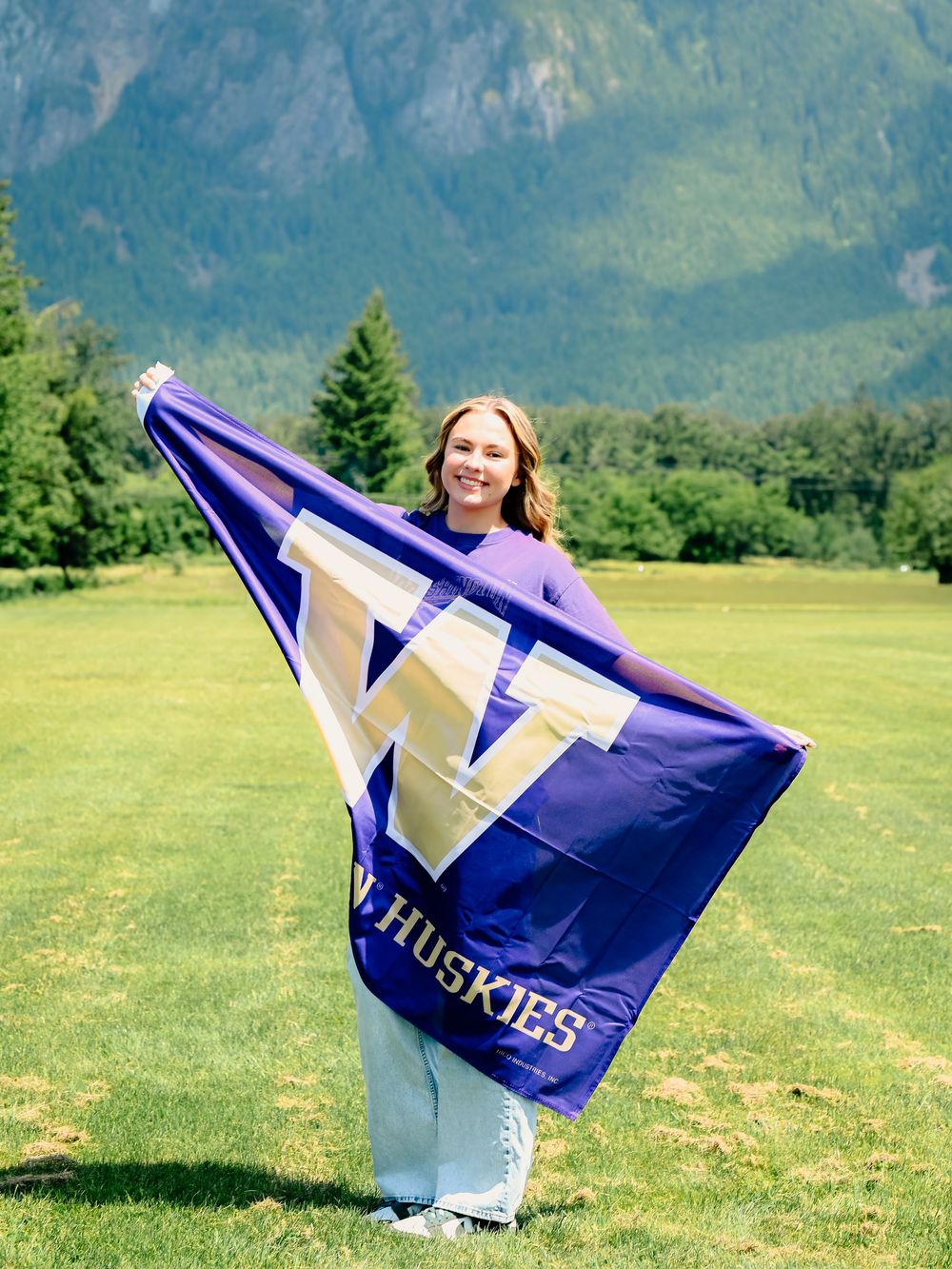 Someone waves a blue and white Huskies flag against a mountain backdrop.