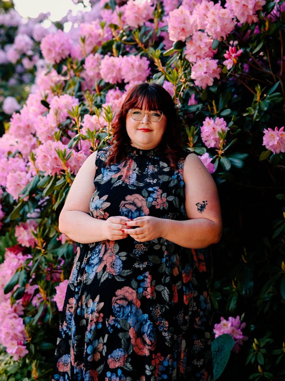 Beautiful floral dress against blooming pink rhododendrons in a garden setting.