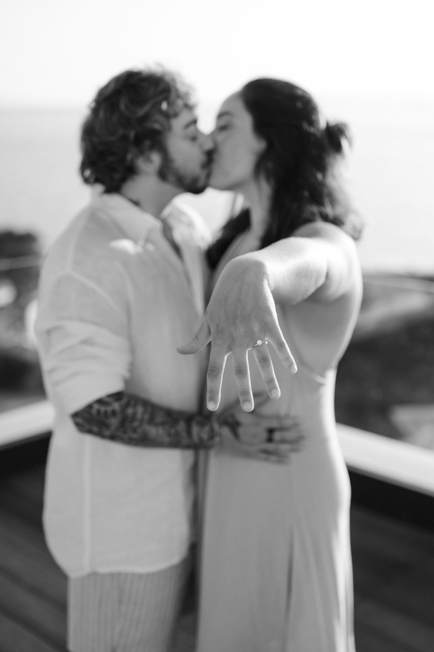 A couple in white attire sharing a romantic kiss during what appears to be their wedding day.