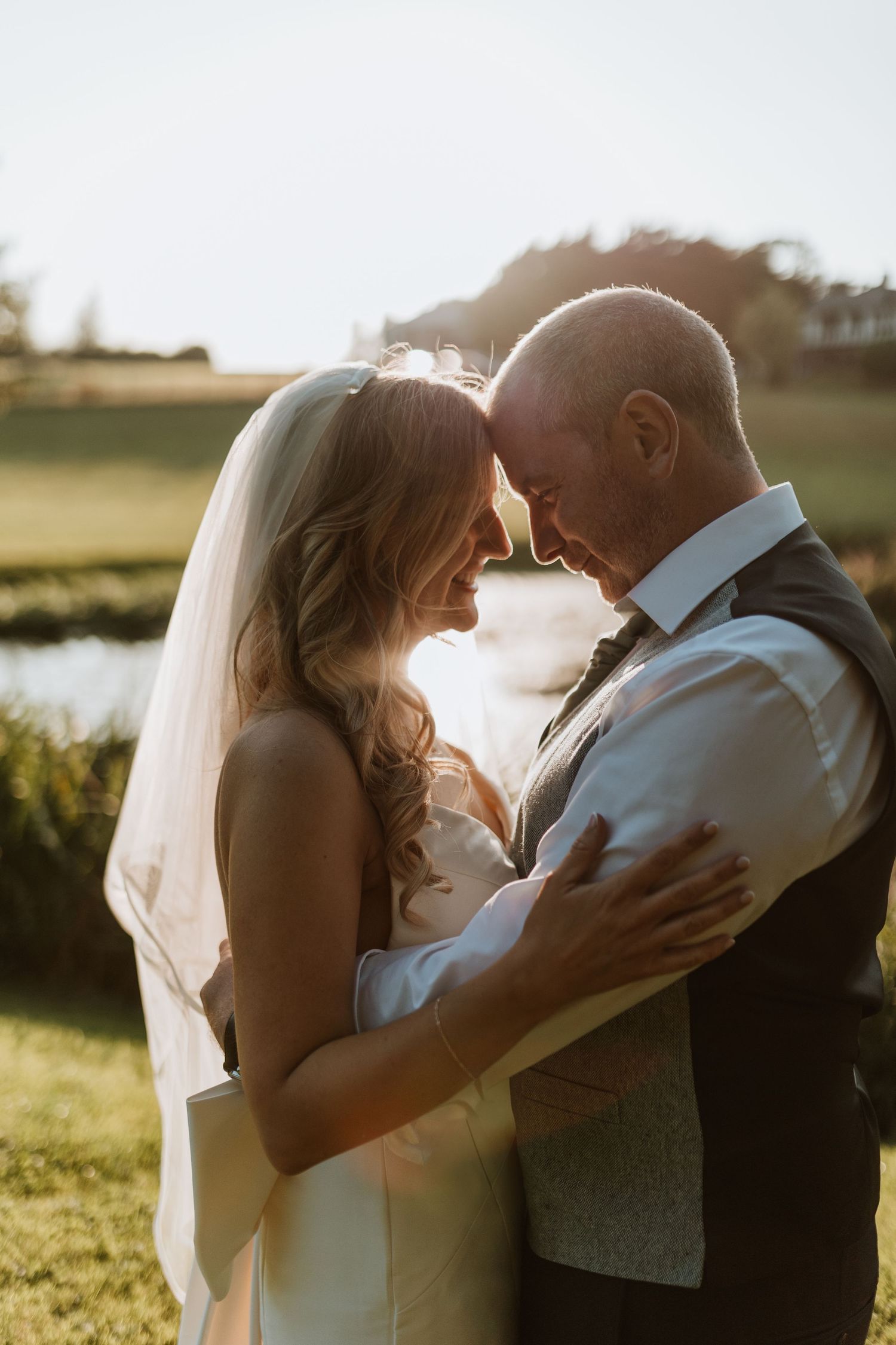 A couple shares intimate moments during their sunset wedding photoshoot in a scenic outdoor location.