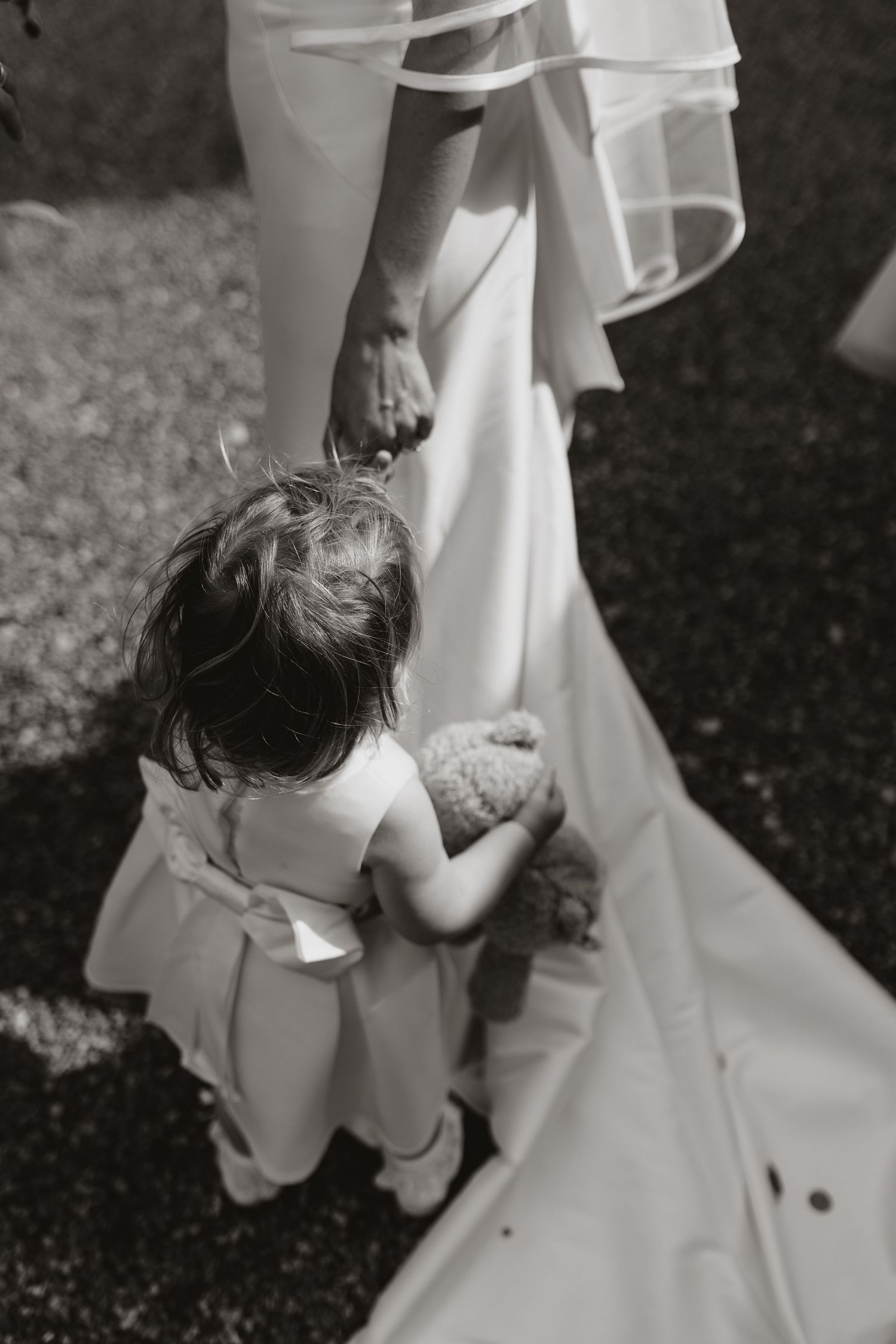 Children playfully hide behind a flowing white bridal gown during a wedding photoshoot.